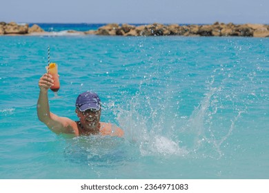 View of happy man with cocktail glass in his han in splashing ocean water. Curacao. - Shutterstock ID 2364971083