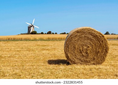 View of a hay bale with a windmill in the background