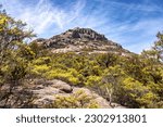 View of the Hazards, a mountain range at Wineglass Bay, Freycinet National Park, Tasmania. Rocky outcrop surrounded by eucalyptus forest. Summer sky background.