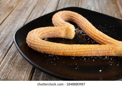 A View Of A Heart Shaped Churro On A Plate.