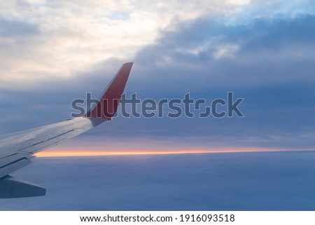 a view from a height above the clouds from the plane's window. part of an airplane wing in the frame