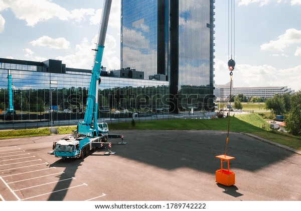 view from the height of the car of a heavy crane\
with a cradle, which is open in the Parking lot and ready to work.\
the highest truck crane is deployed on the site. the height of the\
boom is 80 meters