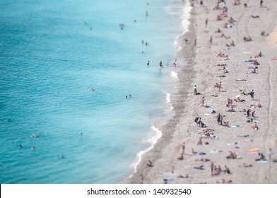 View from height of ocean beach with people bathing in clear blue water and tanning on soft sand. Summer holidays and vacations in hot countries and on resorts. Recreation and tourism.