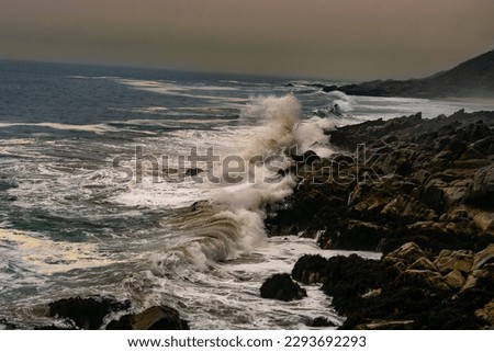 view from the height of the rough waves breaking against the rocks on the coast of the Valparaiso Region, Chile, at sunset