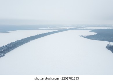 View from a height of a winter landscape with a snowy field, forest and fog - Powered by Shutterstock