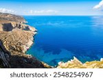 View of high rock cliffs and azure turquoise sea of from Chora village, Folegandros island, Cyclades, Greece