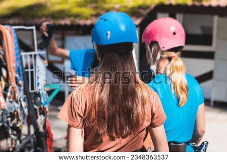 View of high ropes course, process of climbing in amusement acitivity rope park, passing obstacles and zip line on heights in climbing safety equipment gear between the trees om heights, summer day