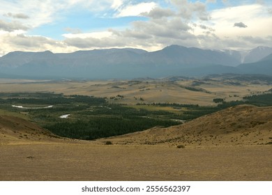 View from the hillsides to the picturesque steppe with a winding river and snow-capped mountain range on a cloudy summer day. Kurai steppe, Altai, Siberia, Russia. - Powered by Shutterstock