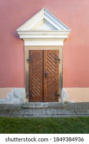 View Of Historic Baroque Wooden Door. Pink Wall And Pediment Above Door