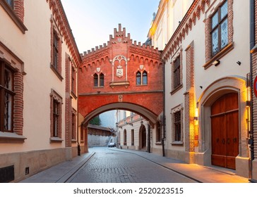 View of a historical archway on Kanonicza Street in Krakow, Poland, with brick facade and illuminated windows - Powered by Shutterstock