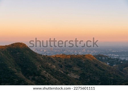 a view of the hollywood mountains during golden hour in with a view of los angeles, california in the background