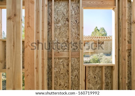 A view of a home in construction, through the window of a construction site. 