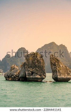 View of Hon Ga Choi Island or Cock and Hen, Fighting Cocks Island located in Ha Long bay, Vietnam, Trong Mai island, junk boat cruise and boats, popular landmark, famous destination Vietnam.