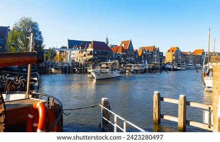 View of Hoorn city port located on lake Markermeer with pleasure boats moored along waterfront and typical townhouses with terracotta tiled roofs on sunny summer day, Netherlands .