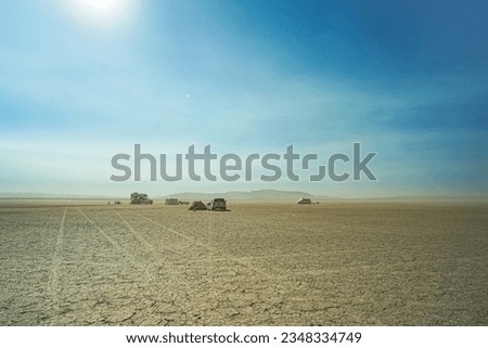 View of the horizon and parked cars in the distance against the background of a blue sky and scorched earth on a dried lake
