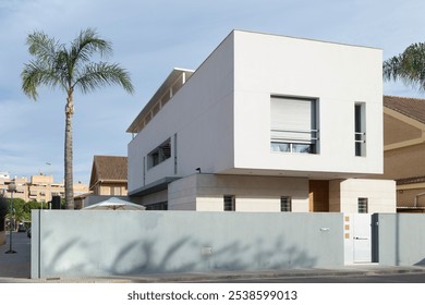 View of a house with contemporary architecture, very modern, with cubic shapes; a palm tree stands out on the side. Sagunto, Valencia, Spain - Powered by Shutterstock