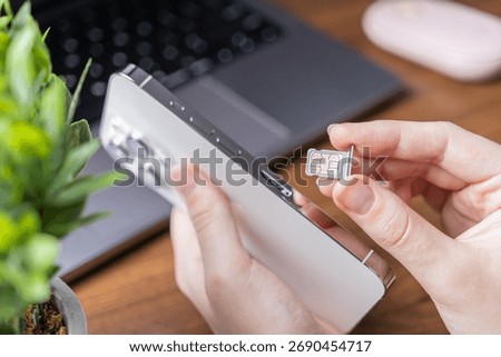 View of human hands inserting a dual nano SIM card into a sleek white mobile smartphone, demonstrating essential telecommunication setup and global data access