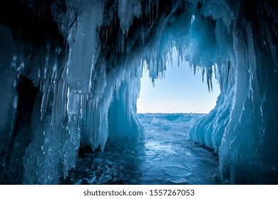View from the ice cave on Lake Baikal. Many beautiful icicles on the walls and ceiling. Thick and thin icicles. Ice on the floor.