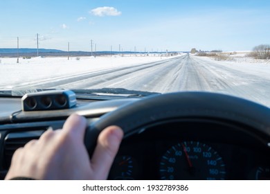 view of the icy, slippery, dangerous road, highway against the background of the driver's hand at the wheel of the car