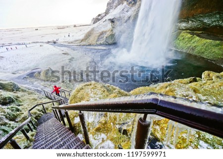 View of the icy walking path next to Seljalandsfoss waterfall in winter in Iceland.