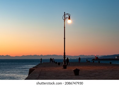 View of the illuminated street lantern in the Molo Audace pier of Trieste in a winter evening  - Shutterstock ID 2086747930