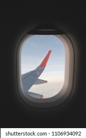 View From Inside Airplane Window. Looking Outside At The Airplane Wing Seeing Clouds And A Blue Sky.