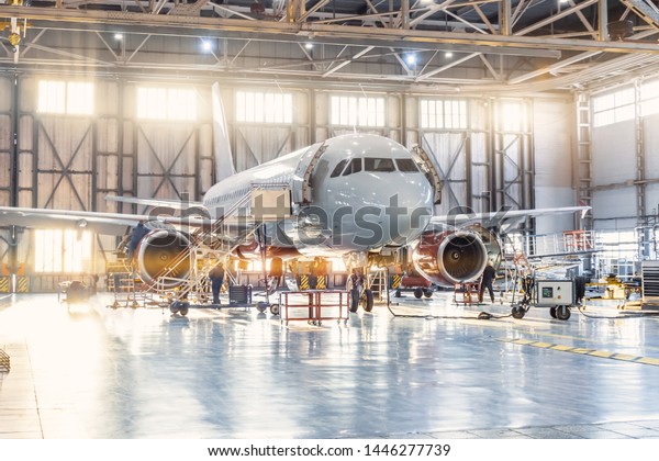 View inside the aviation hangar, the airplane\
mechanic working around the\
service