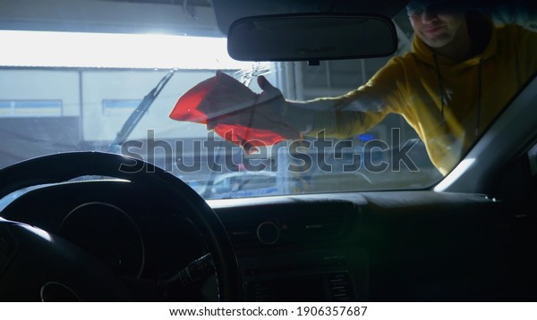 view from inside the car. a man washing a car at a\
car wash.