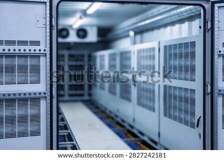 A view inside a climate-controlled containerized data center featuring rows of server cabinets and a battery backup system with visible cabling