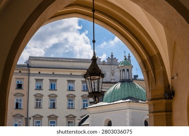 A view from inside the Cloth Hall in Kraków looking out onto the Main Market Square, showing the historic Church of St. Adalbert (Kościół św. Wojciecha) with its distinctive green dome. Krakow, Poland