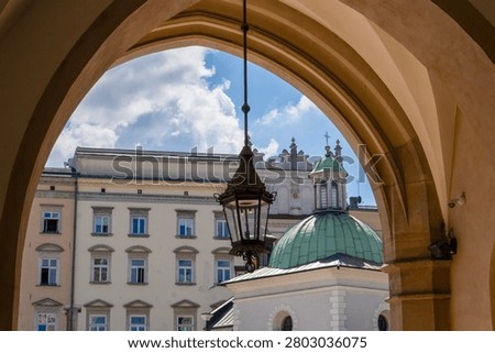 A view from inside the Cloth Hall in Kraków looking out onto the Main Market Square, showing the historic Church of St. Adalbert (Kościół św. Wojciecha) with its distinctive green dome. Krakow, Poland
