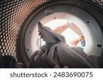 View from inside the drum of a washing machine: a man loads or unloads laundry. Laundry.
Interior view of the washing machine.