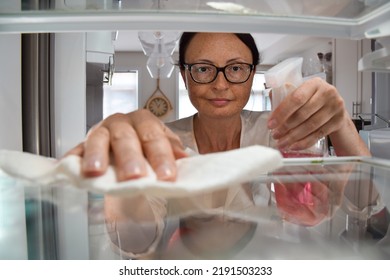 View From Inside The Fridge Of Middle Aged Woman Cleaning Shelves