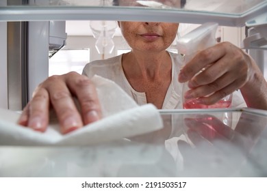 View From Inside The Fridge Of Woman Cleaning Shelves