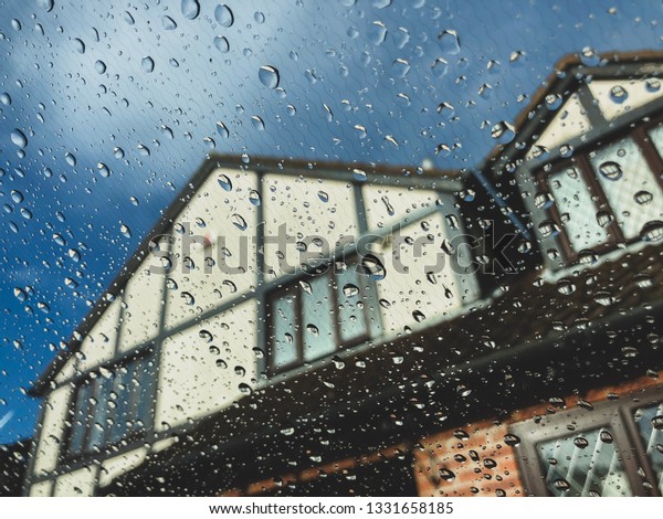 View from inside a glass window of rain drops\
against a blue sky.