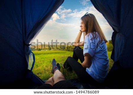 View from inside of tent. Man lying in tent and looking for his girlfriend. Hiking in mountains. Satisfaction from solitude together in nature