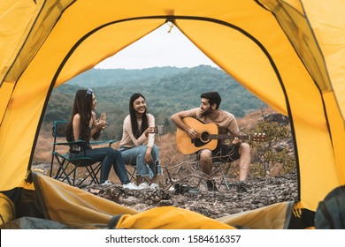 View from the Inside of Tent show group of friend have fun playing guitar and sing along at the mountain. Relaxation Camping concept - Powered by Shutterstock