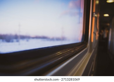 A view from inside a train car at sunset through the glass on a cold winter evening in a cozy train on a long journey