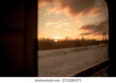 A view from inside a train car at sunset through the glass on a cold winter evening in a cozy train on a long journey
