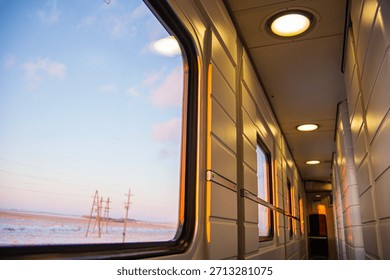 A view from inside a train car at sunset through the glass on a cold winter evening in a cozy train on a long journey