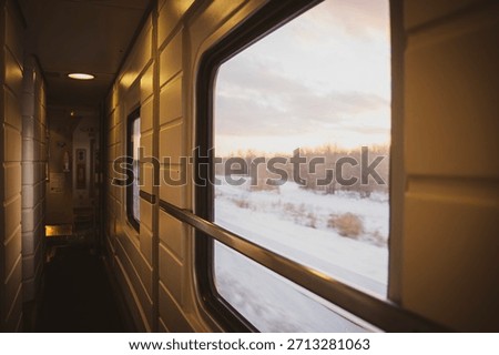 A view from inside a train car at sunset through the glass on a cold winter evening in a cozy train on a long journey