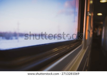 A view from inside a train car at sunset through the glass on a cold winter evening in a cozy train on a long journey