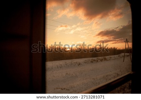A view from inside a train car at sunset through the glass on a cold winter evening in a cozy train on a long journey