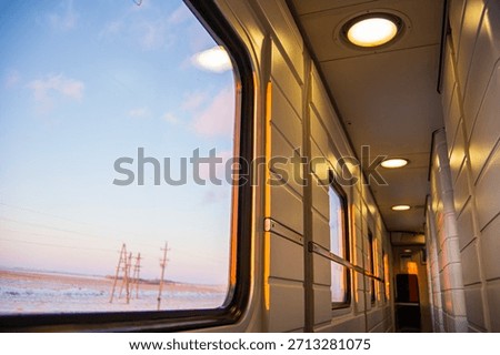 A view from inside a train car at sunset through the glass on a cold winter evening in a cozy train on a long journey