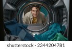 View from inside the washing machine, adult man looking at the camera and smiling