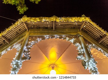 View Of The Interior Of A Cubicle In The Center Of A Square Decorated With Christmas Motifs And Lights, On A Beautiful Night