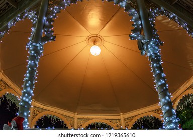 View Of The Interior Of A Cubicle In The Center Of A Square Decorated With Christmas Motifs And Lights, On A Beautiful Night