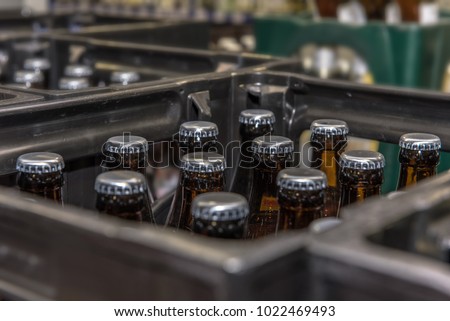 View into a beer crate standing in a beverage market. Crate with full beer bottles. Focus on the bottles. Concept: drinks
