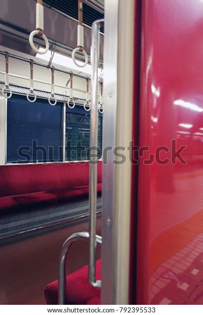 View into an empty Car of a Japanese Regional\
Train with red benches