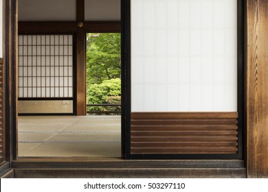 View into a japanese room with open shoji door and green garden in the background.